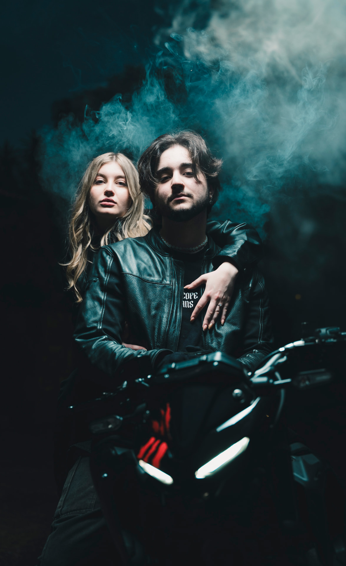Casal em moto com fumaça azul à noite